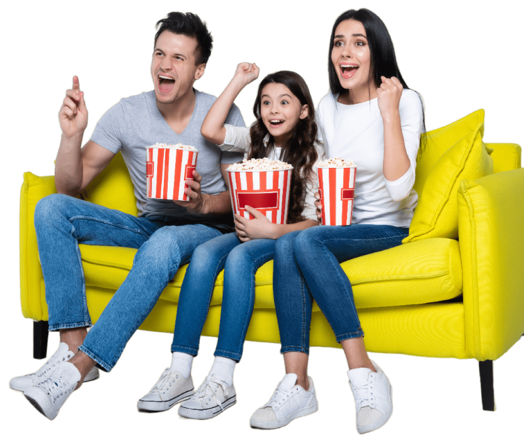 A family of three is sitting on a bright yellow couch, enjoying a movie night. They are holding red-and-white striped popcorn buckets and appear excited, with their arms raised in enthusiasm. The scene conveys a sense of fun and togetherness.